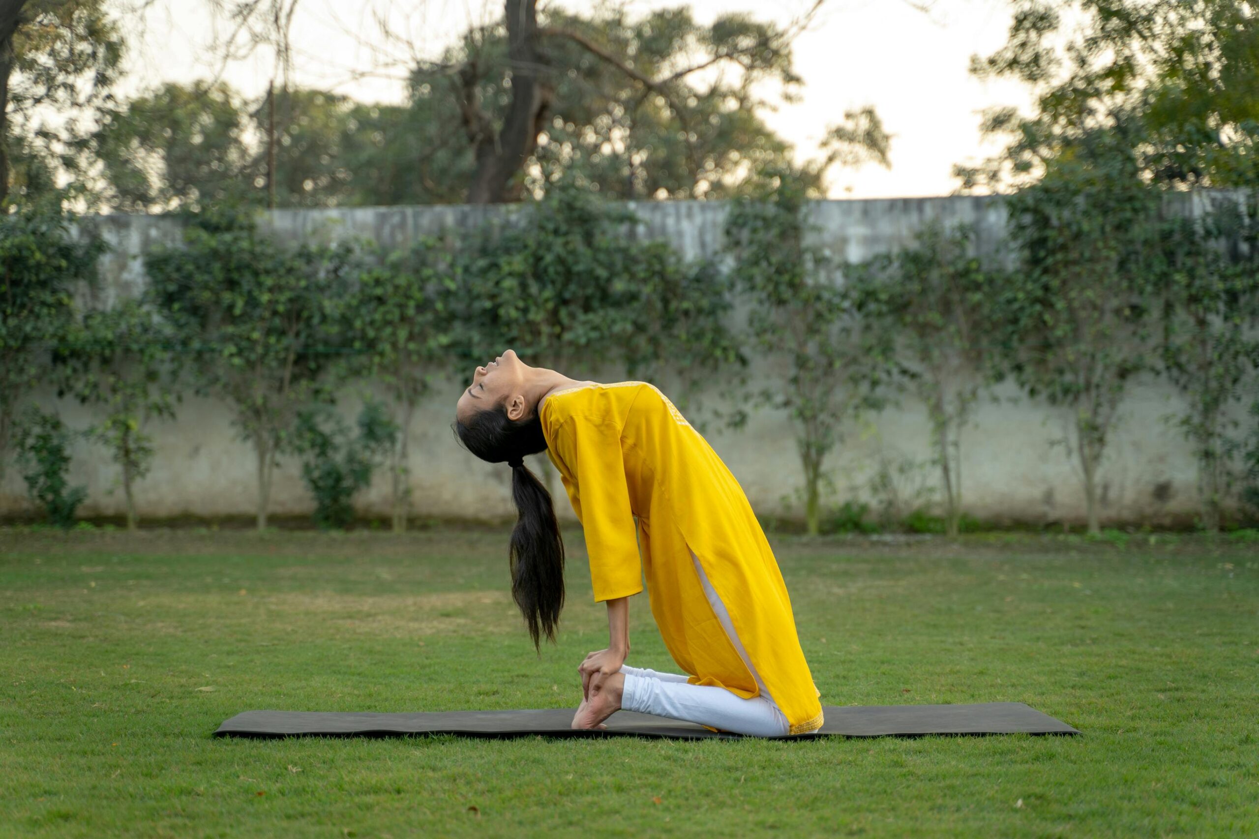 Woman in Yellow Long Sleeve Dress Sitting on Black Mat on Green Grass Field